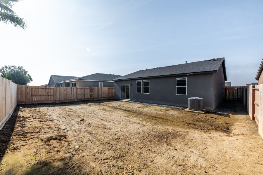 A dirt yard with a house in the background.
