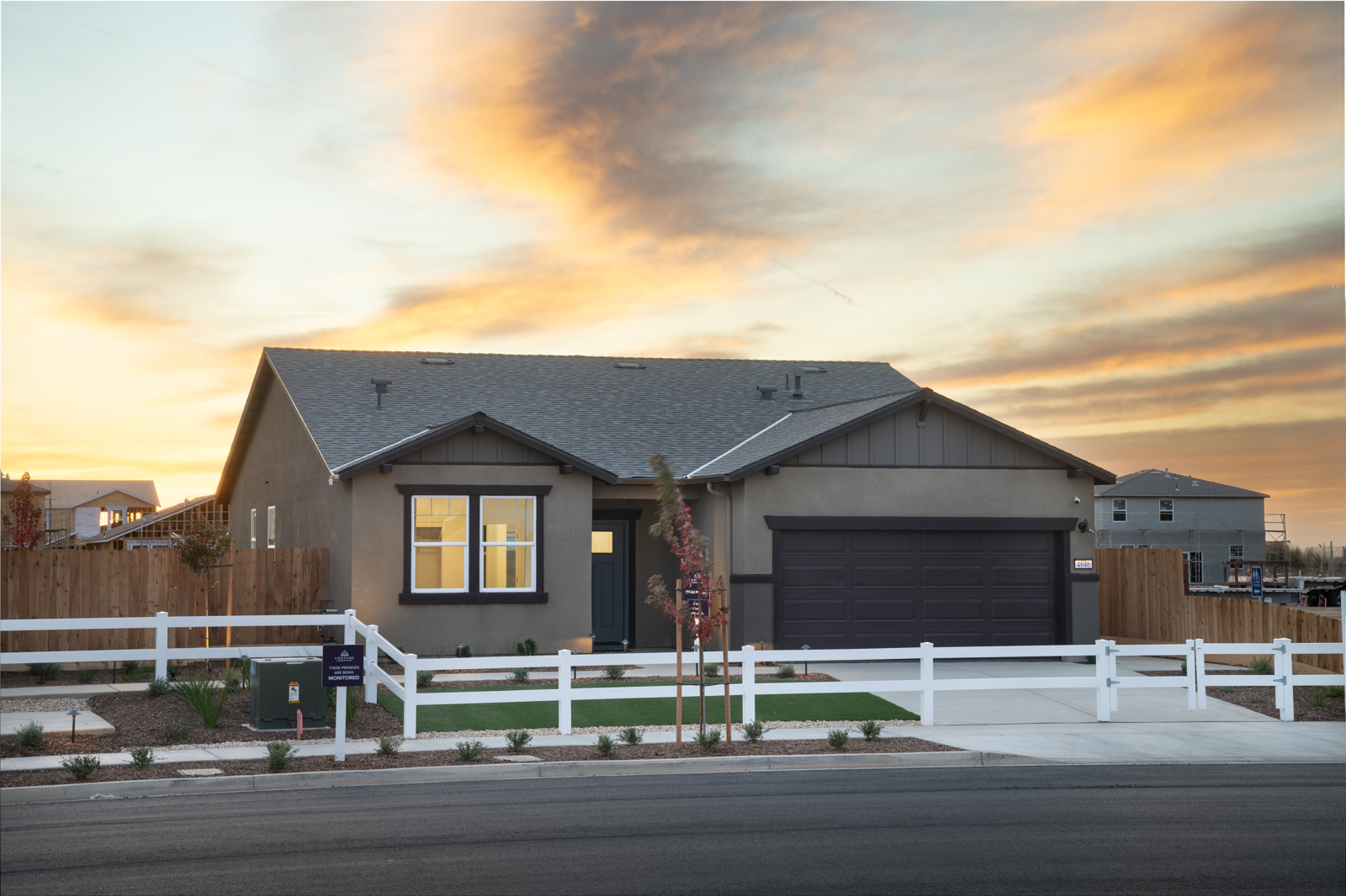 A house with a garage and a fence in front of it.