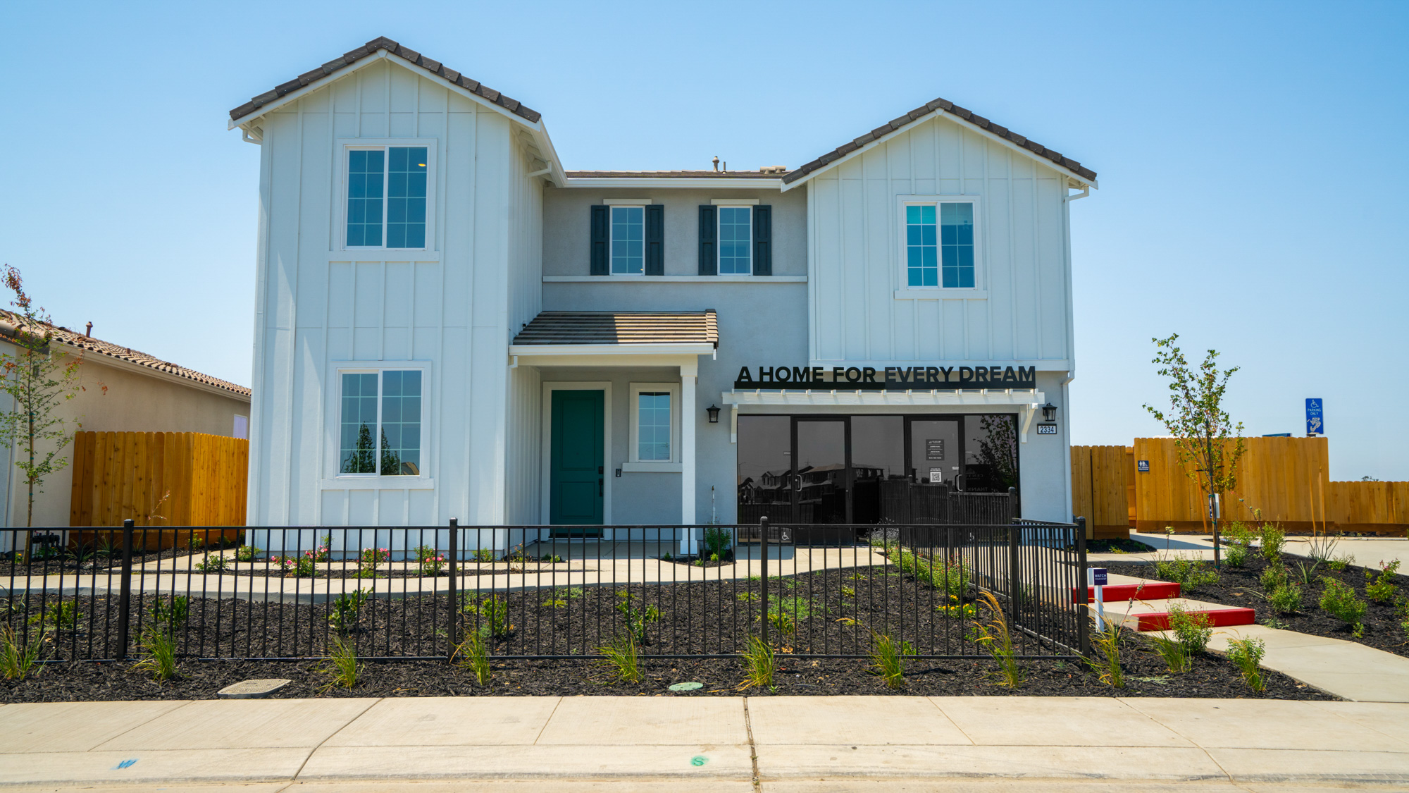 A white building with a black fence.
