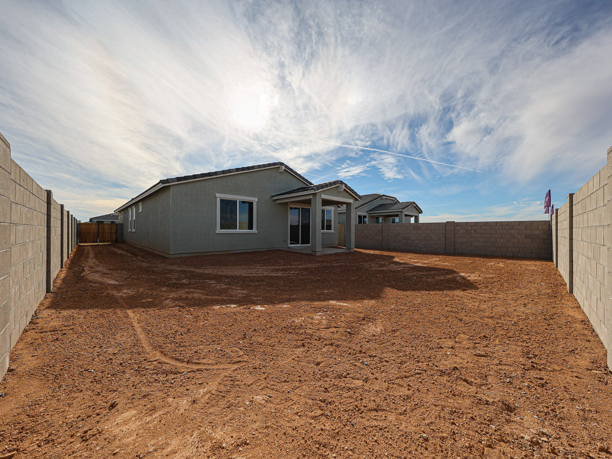 A dirt yard with a house in the background.
