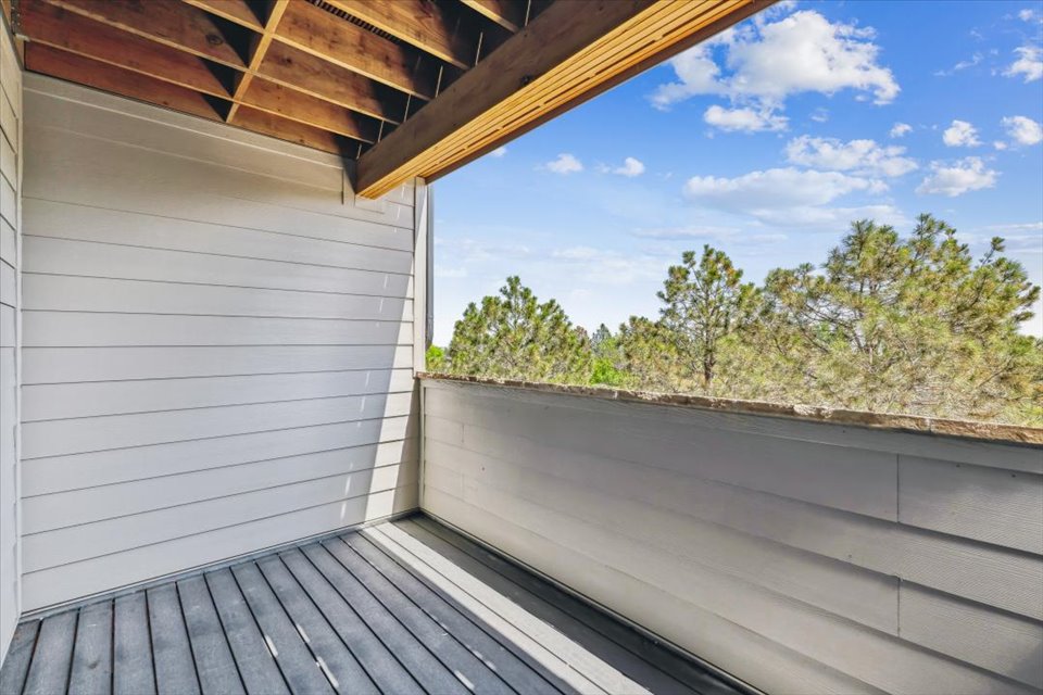 A deck with a wood railing and trees in the background.