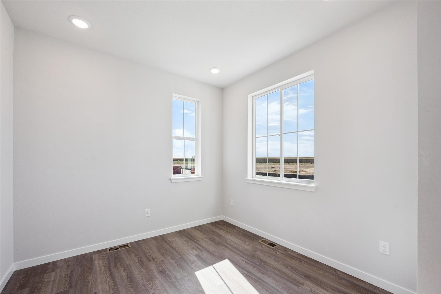 A room with a wood floor and windows.
