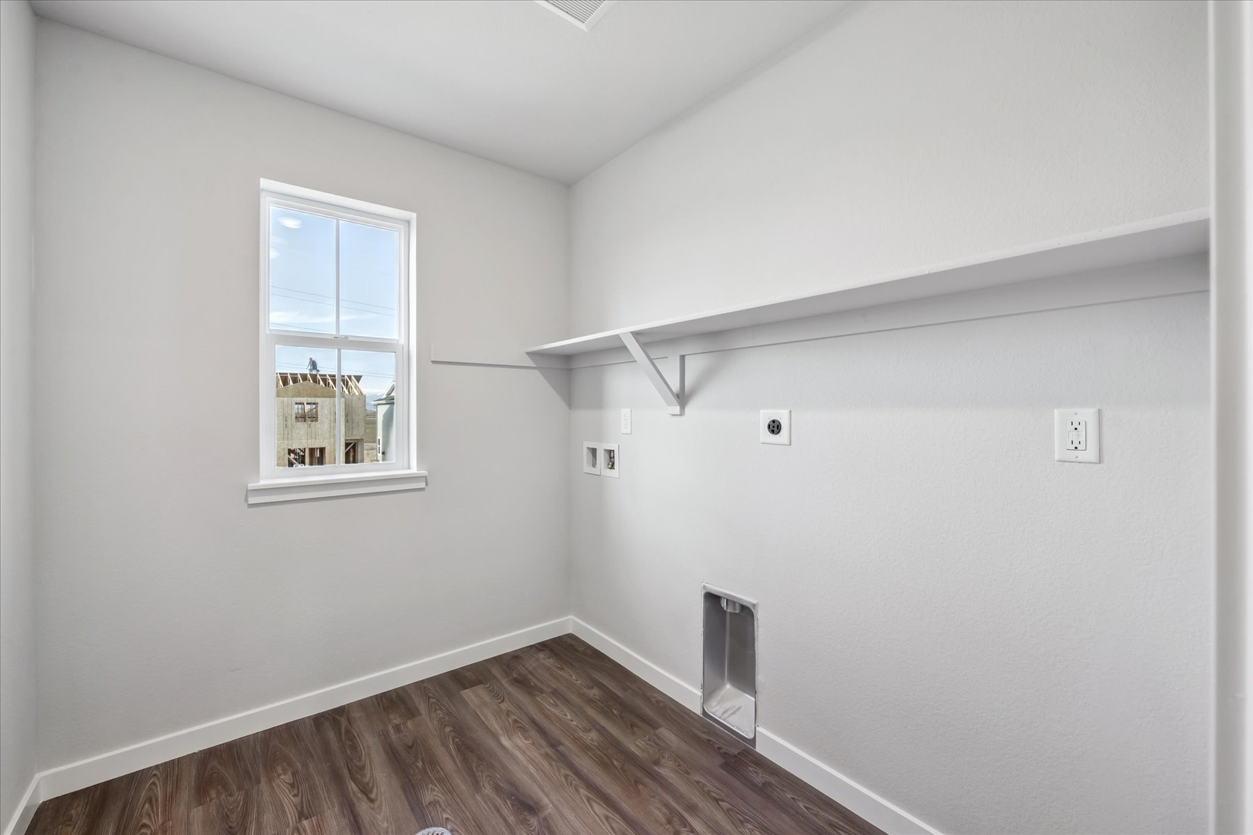 A room with a window and a wood floor.