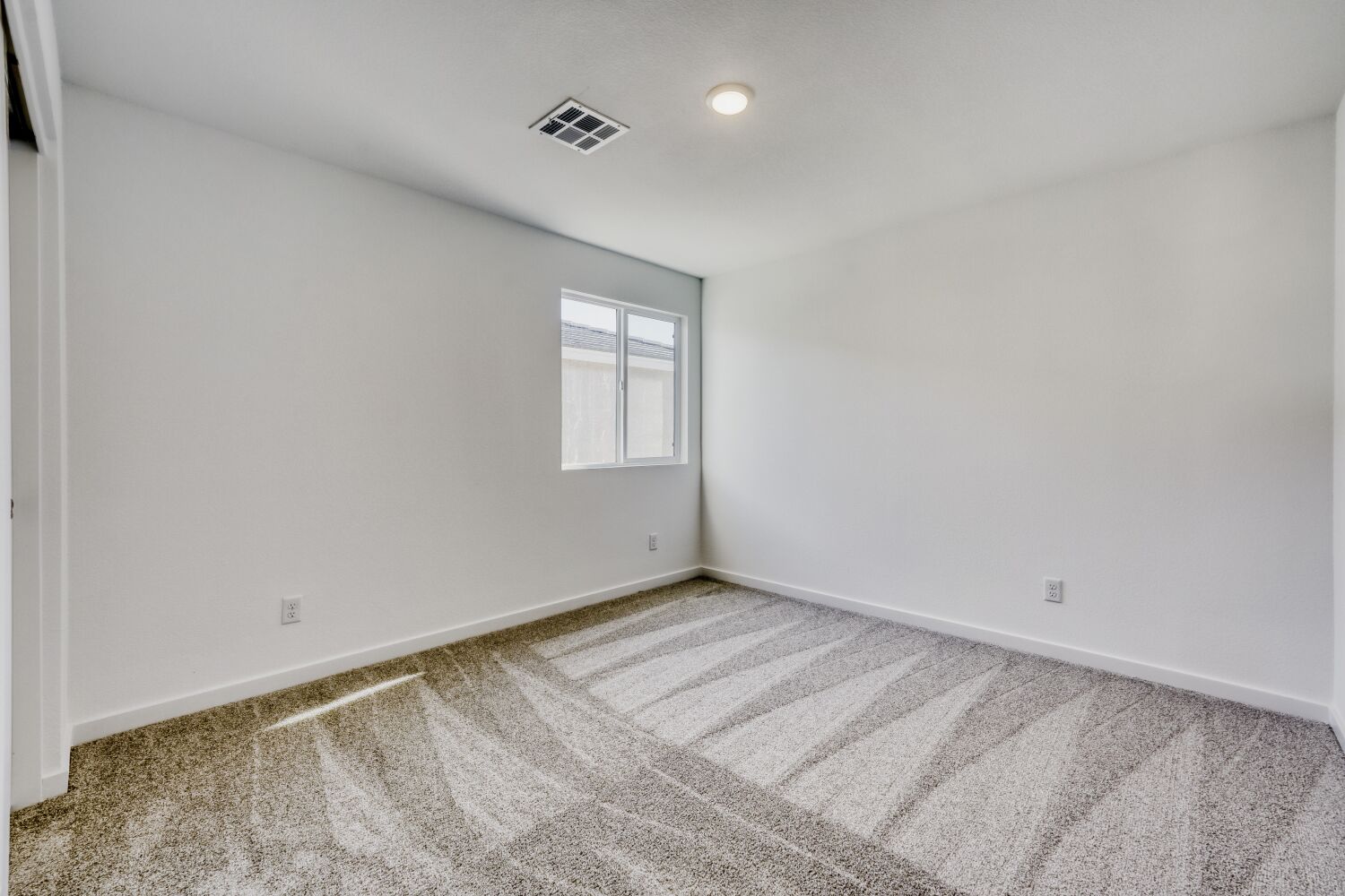 A room with a carpet and a window.