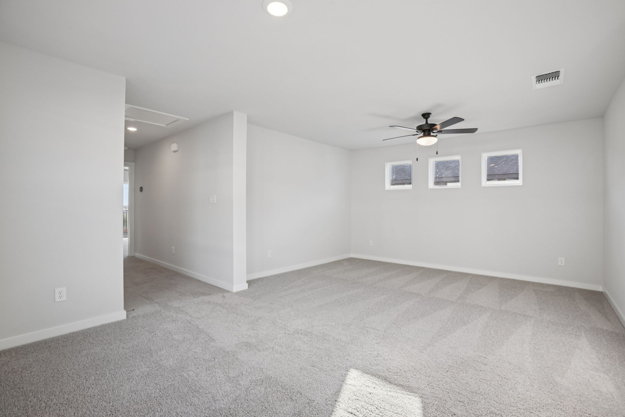 A room with a ceiling fan and a door.