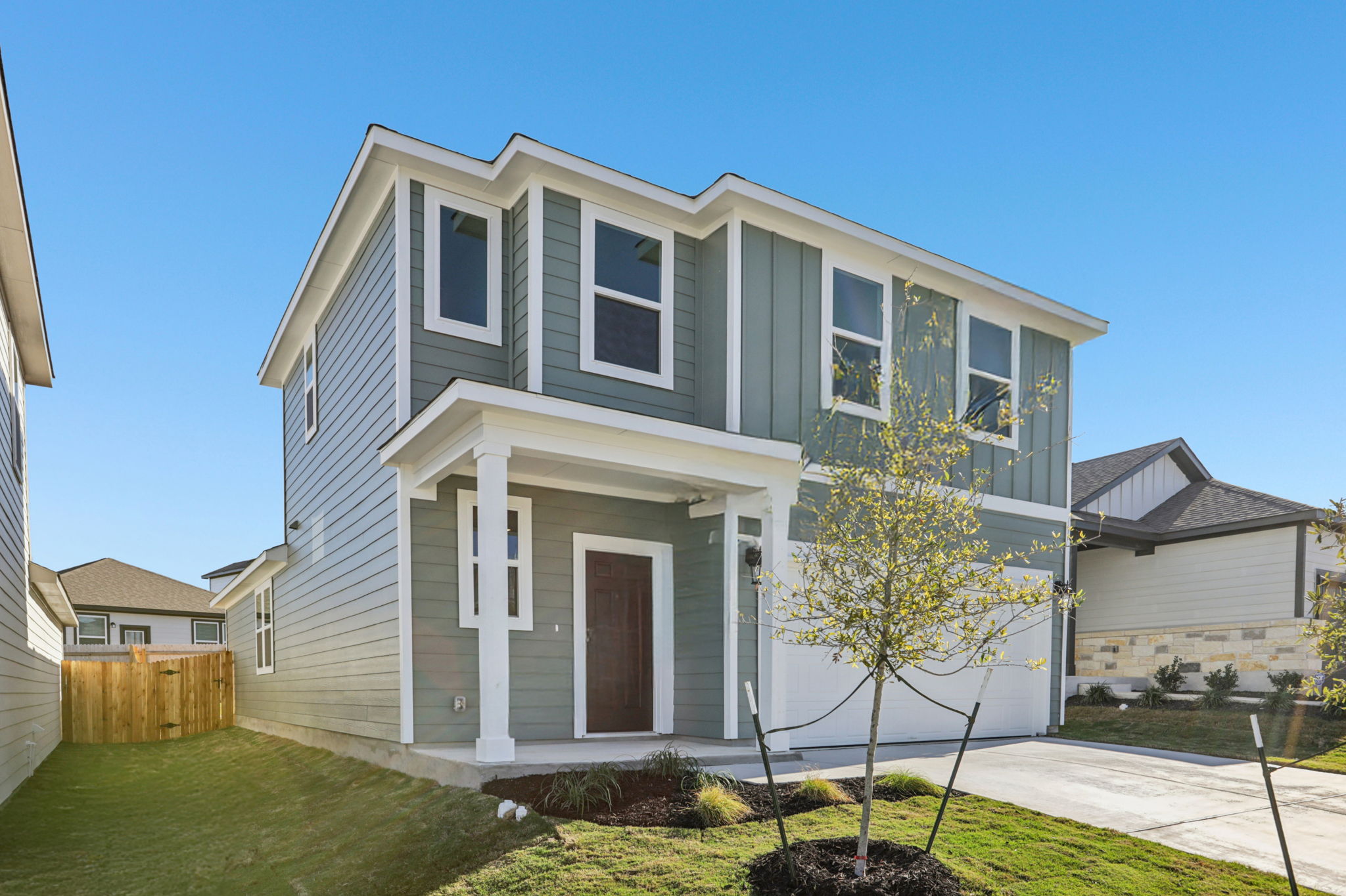 A white house with a tree in the front.