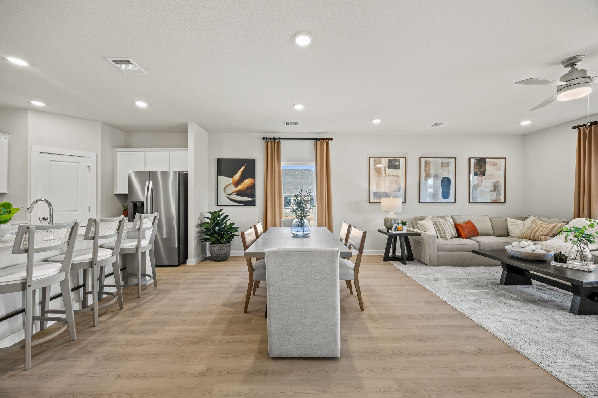 A large living room with a wood floor and a large dining table.