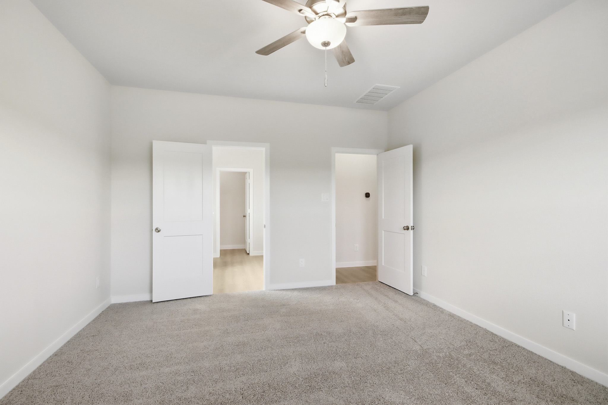 A room with white doors and a ceiling fan.
