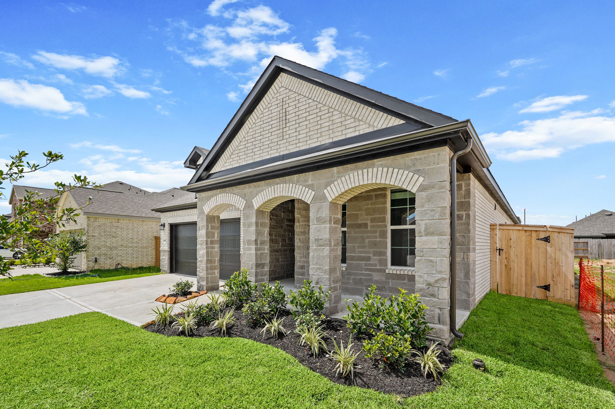 A house with a fence and a yard with a brick building.