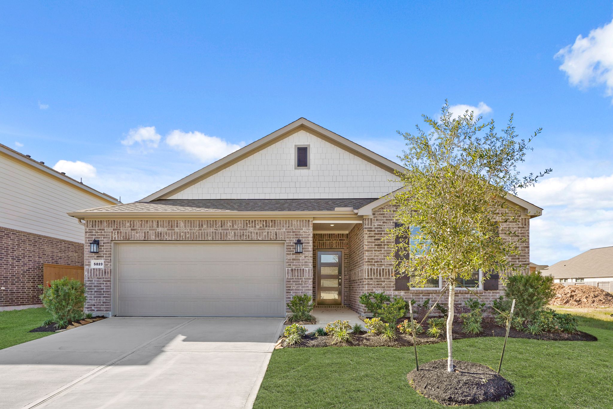 A house with a garage and a tree in the front.