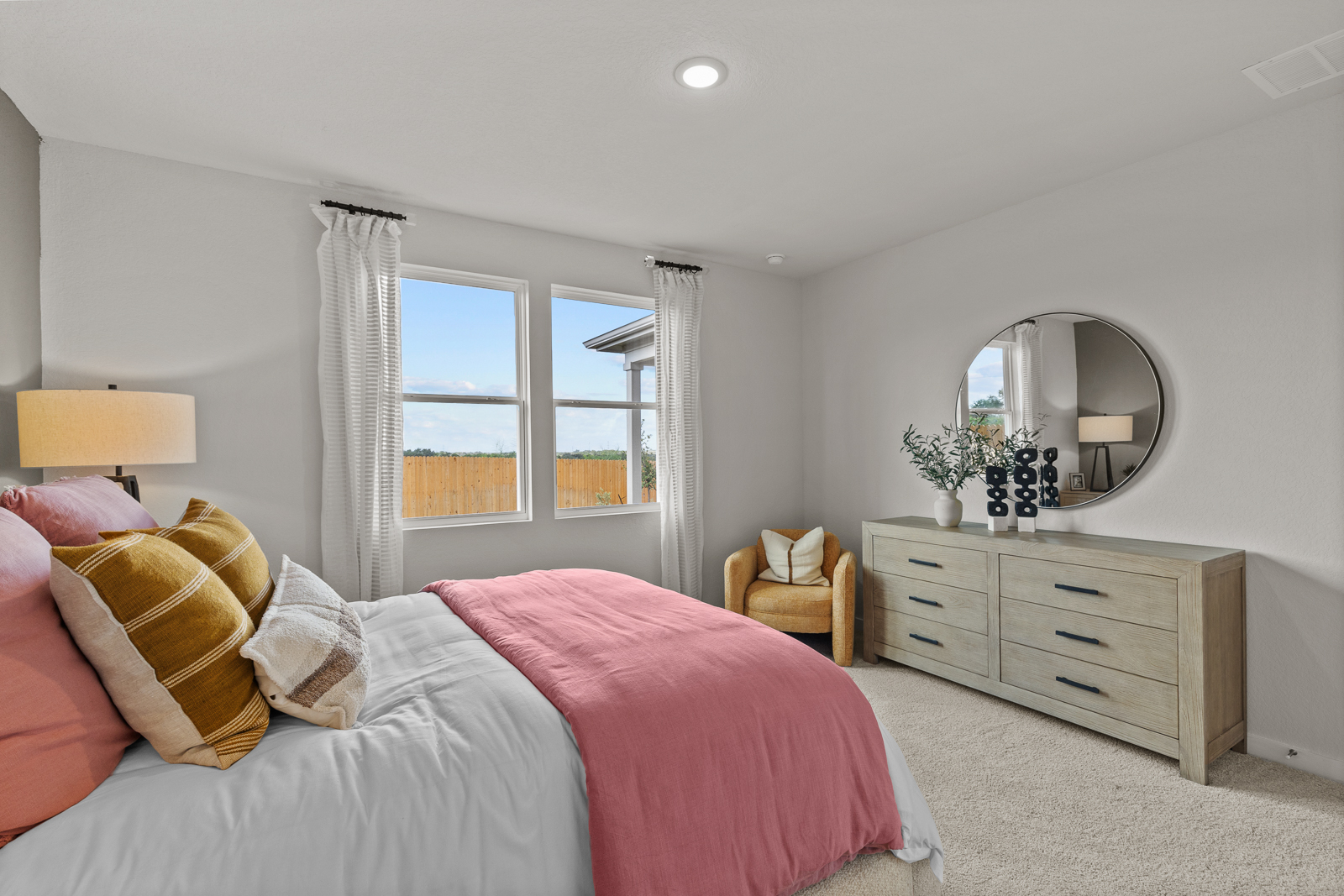 A bedroom with a pink bed and pink pillows.