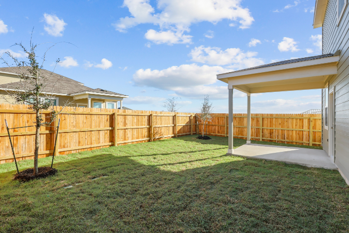 A backyard with a fence and trees.