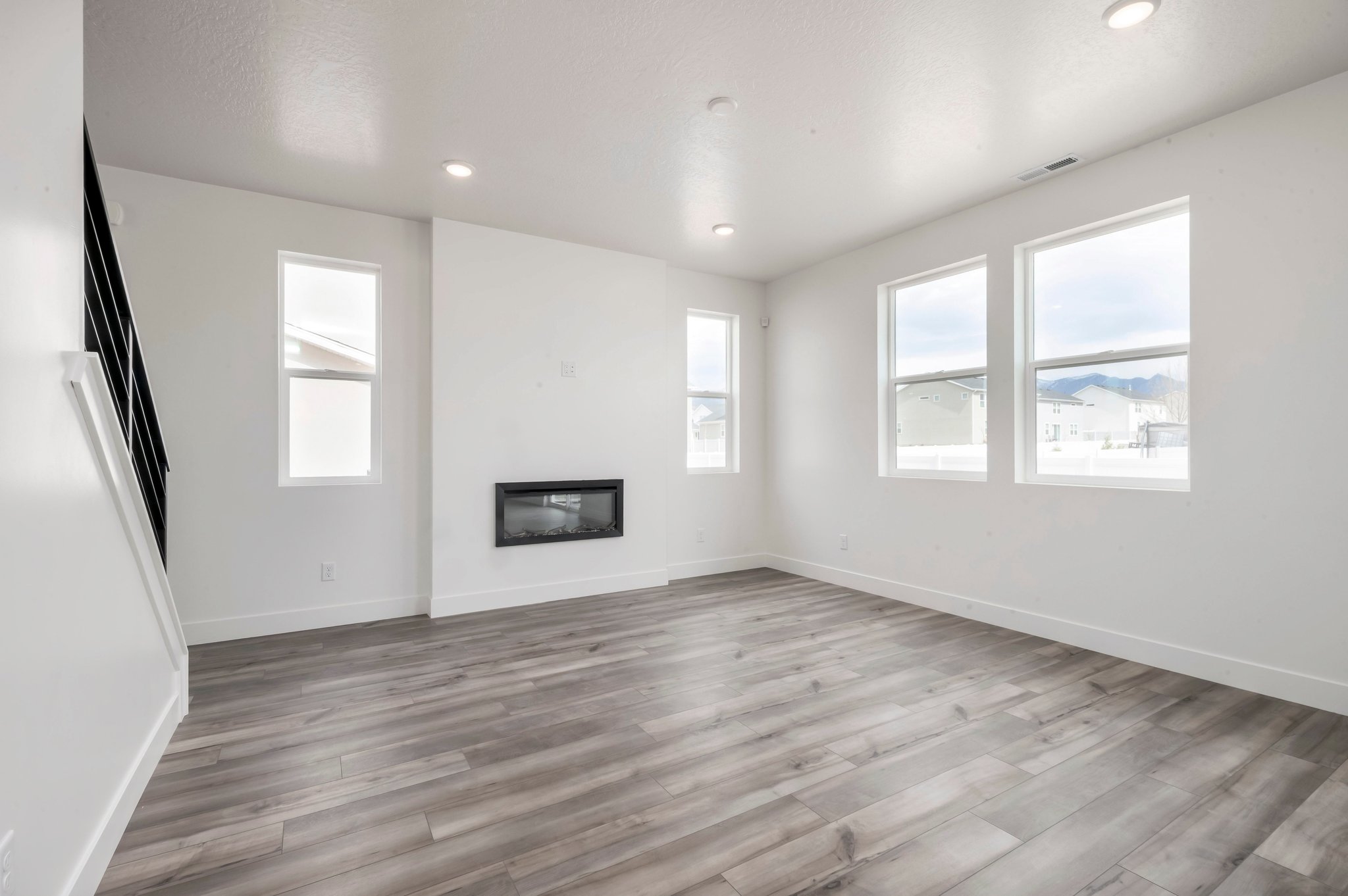 A room with a wood floor and a window with a view of the city.