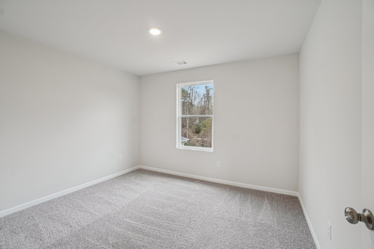 A room with a white wall and a painting on the wall.