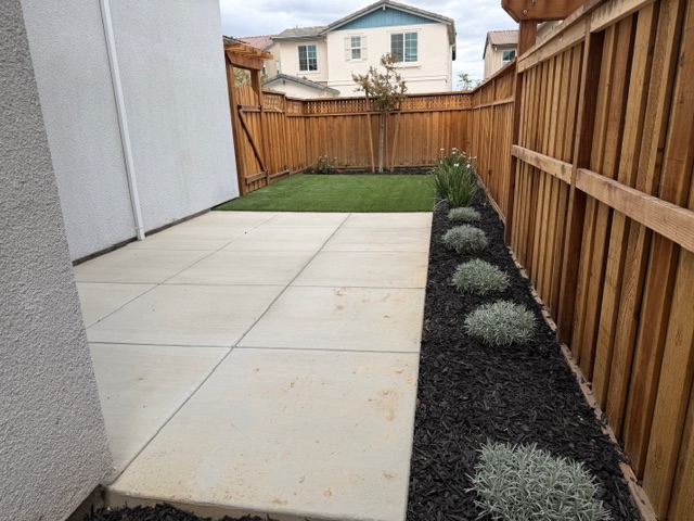 A backyard with a fence and a house.